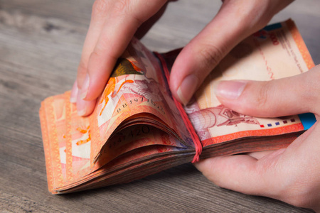 手拿着一沓带着松紧带的钱.腾格kzt.哈萨克斯坦国家货币,kz.汇率.