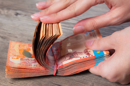 发展国家手拿着一沓带着松紧带的钱.腾格kzt.哈萨克斯坦国家货币,kz.