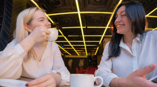 两个微笑的女孩在咖啡馆喝咖啡