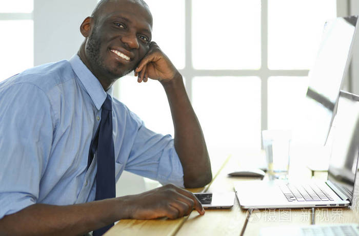 非洲裔美国商人戴着耳机在笔记本电脑上工作