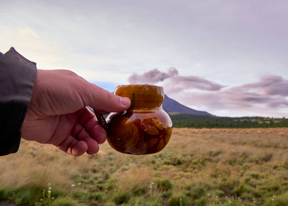 年轻人拿着咖啡杯，背景是波波卡特佩特火山