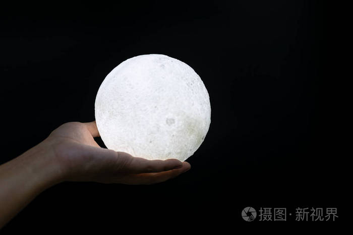 晚上一只手拿着月亮模型的照片