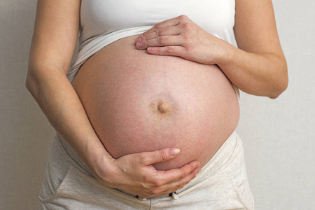 孕妇的肚子。孕妇双手放在白色背景上的腹部。怀孕生育准备和期望概念
