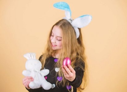 鸡蛋盛宴。拿着复活节彩蛋和兔子玩具的小女孩。可爱的孩子带着复活节兔子带着蛋吃。复活节彩蛋白兔小孩儿
