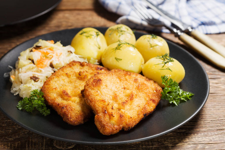 Fried pork chop in breadcrumbs, served with boiled potatoes and 