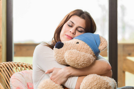快乐的年轻女人拥抱着一只大泰迪熊。