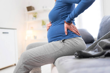 怀孕累得筋疲力尽的孕妇胃部问题和背部疼痛照片