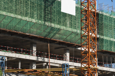 蓝天下的起重机和建筑工地。未完工建筑的金属结构。塔吊用于多仓库建筑。