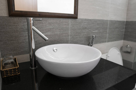 浴室内部有白色圆形水槽和现代浴室的镀铬水龙头。
