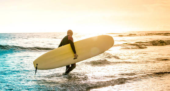 孤独的冲浪者在特内里费日落时用长板行走冲浪冒险生活方式和运动旅行理念彩色阳光过滤色调