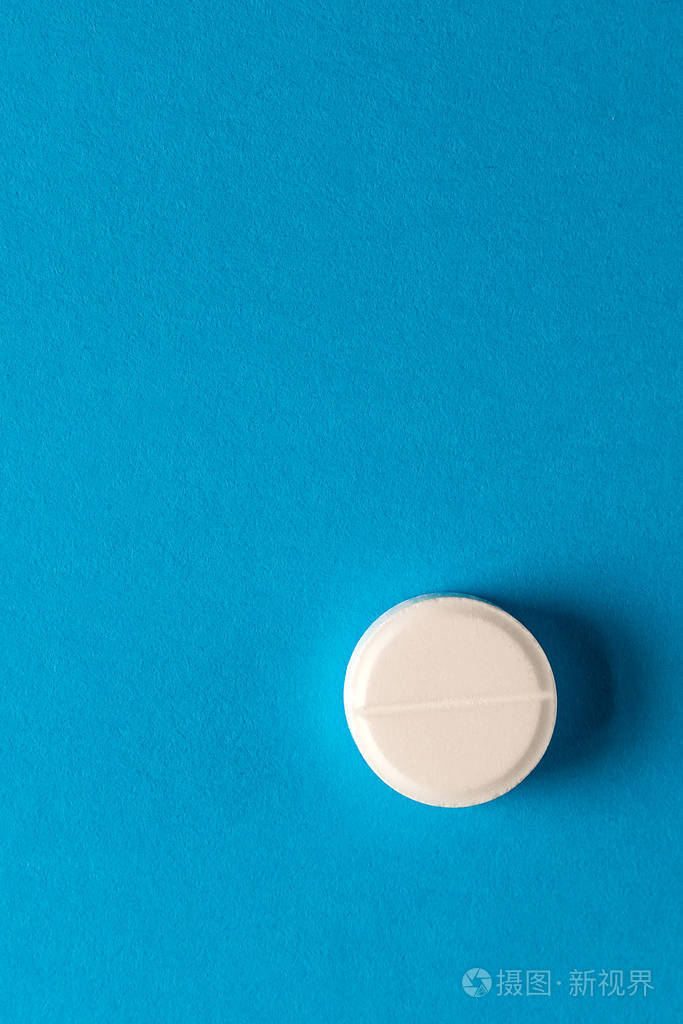 一颗蓝色背景的白色药丸复制空间医学健康垂直照片