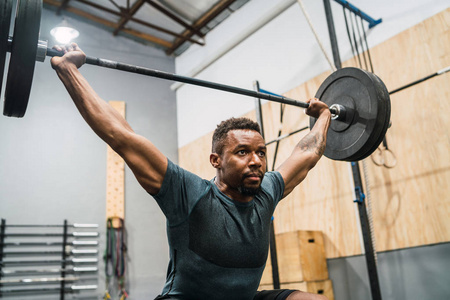 Crossfit athlete doing exercise with a barbell. 