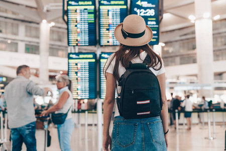 在机场背着背包戴着帽子的游客看着登机牌