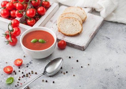 White bowl plate of creamy tomato soup with spoon on light table