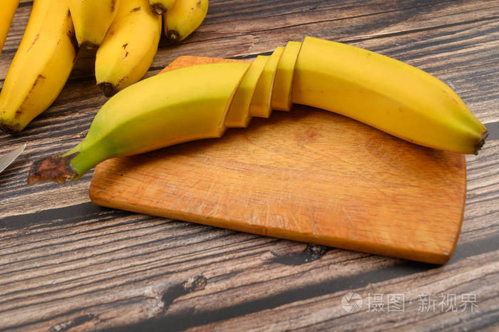 一根成熟的黄色香蕉在木质背景的木板上切成几块闭合