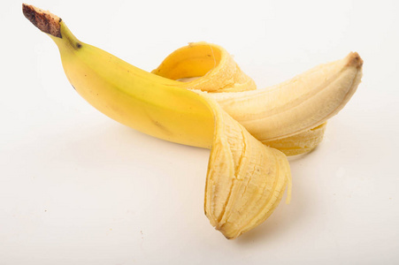 闭合的曲线一个成熟的黄色部分去皮的香蕉,背景为白色.闭合.照片
