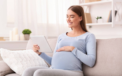 孕妇坐在沙发上看电子书图片