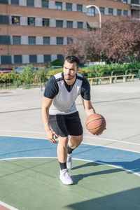 在城市篮球场上，篮球运动员用左臂移动球