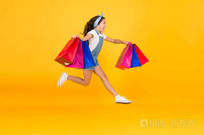 趋势和品牌折扣快乐的女孩拿着购物袋跳起来小孩子拿着纸袋微笑假期