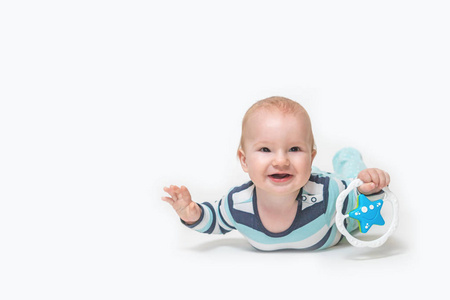 Laughing  baby boy is lying on white background holding a toy. 
