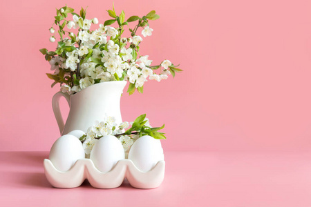 一束春天的花朵插在花瓶里，鸡蛋放在粉红色的桌子上。文本空间。