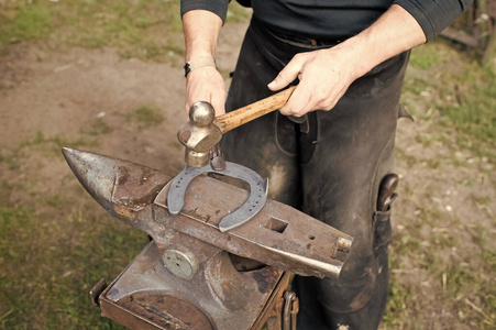 铁匠用铁锤在铁砧上锻造马蹄铁。古老的工艺。乡村手工艺。加工金属的铁匠。车间工艺工具。铁匠职业概念