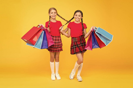 拿着购物袋的女孩。重新发现伟大的购物传统。购物和购买。黑色星期五。销售折扣。礼品和纪念品。和朋友一起购物。孩子们拿着包裹。有史以