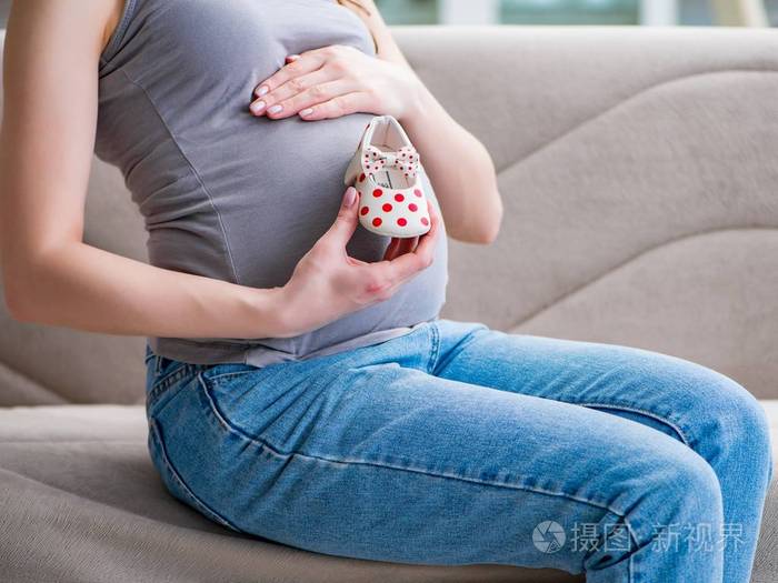 肚子大的孕妇坐在家里的沙发上