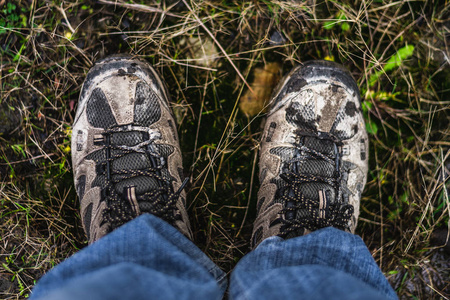 在草地上徒步鞋一双沾满泥巴的雄性步行鞋站在从上方拍摄的草地上