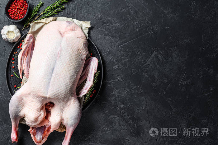 生的整鸭粉胡椒和迷迭香黑色背景俯视图文本空间