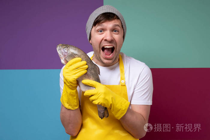 雄渔民用黄色围裙抱着一条大马哈鱼鳟鱼