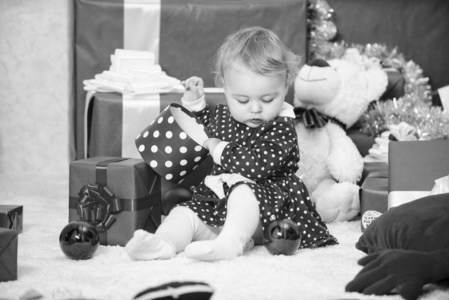 圣诞节和学步儿童的事。儿童第一个圣诞节礼物。小女婴在一堆礼盒旁玩耍。家庭假日。幼儿圣诞活动。幼儿圣诞礼物