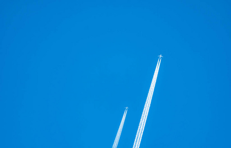 Two airplane with white condensation tracks. Jet plane on clear 