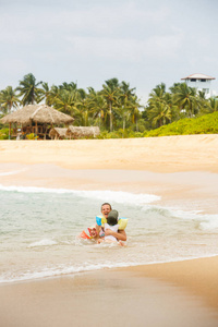 Mother enjoying a tropical beach, playing in the waves with her 