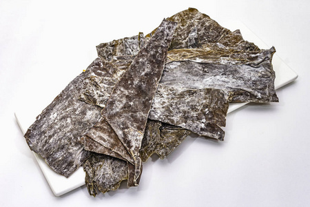 白色背景下分离的干海带.日本传统的烹调大石汤的原料照片