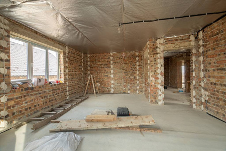 Interior of unfinished brick house with concrete floor and bare 