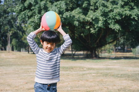 在公园的草坪上玩球的亚洲小男孩是户外的