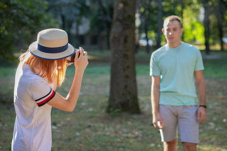 Young teenage couple taking pictures of one another outdoors in 