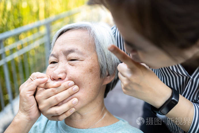 愤怒的亚洲女性捂着老人的嘴表现出沉默的姿态保持秘密安静社会暴力