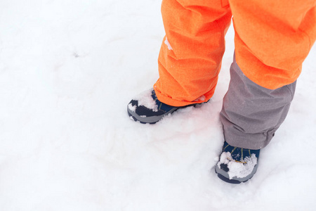 穿冬天靴子的孩子站在雪地上