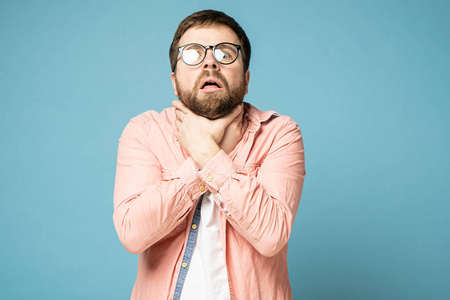 男子感到喉咙疼痛或勒死自己,双手捂住脖子,面对镜头显得很害怕.照片