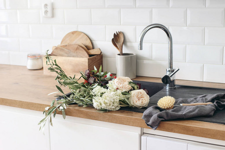 白砖墙,地铁瓷砖,木制台面和厨房用具.玫瑰在黑色水槽里盛开.