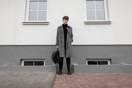 Fashionable young man in a gray elegant plaid coat with a leathe