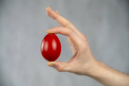 在手指之间复活节红鸡蛋夹在手指之间,白色抽象背景.照片