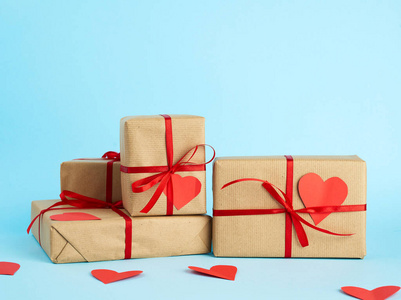 stack of wrapped gifts in brown kraft paper and tied with a red 