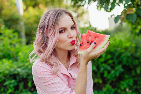 粉红色头发的年轻漂亮女人在吃西瓜