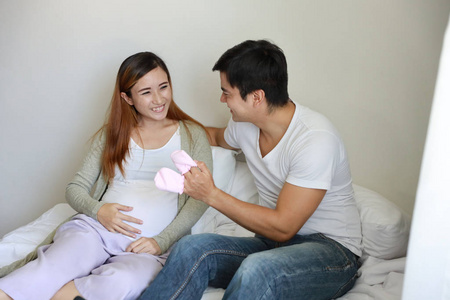 Close up asian pregnant woman and caucasian husband sitting on b