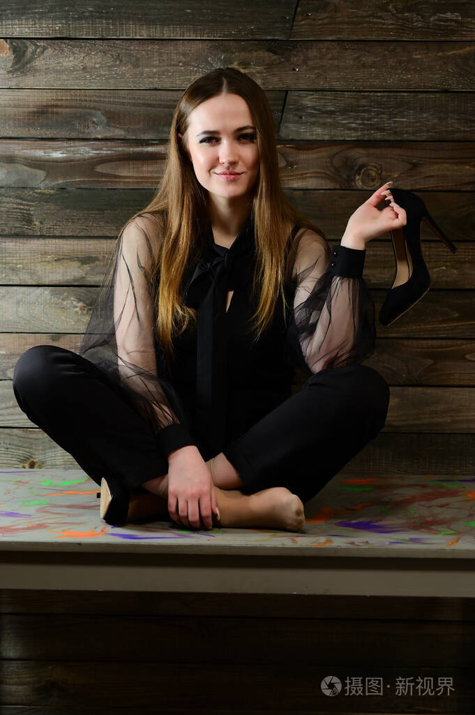 一张全身照片是一个可爱的黑发女人,穿着深色衣服,妆容很好,坐在家里