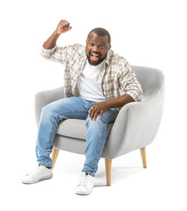 Emotional AfricanAmerican man watching TV while sitting in armc