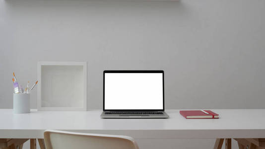 Cropped shot of workspace with open blank screen laptop, frame, 